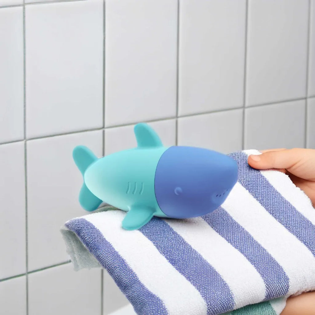 Toddler squeezing Squeezi Shark in the bathtub for water play