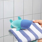 Toddler squeezing Squeezi Shark in the bathtub for water play