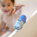 Toddler squeezing Squeezi Hippo in the bathtub for water play