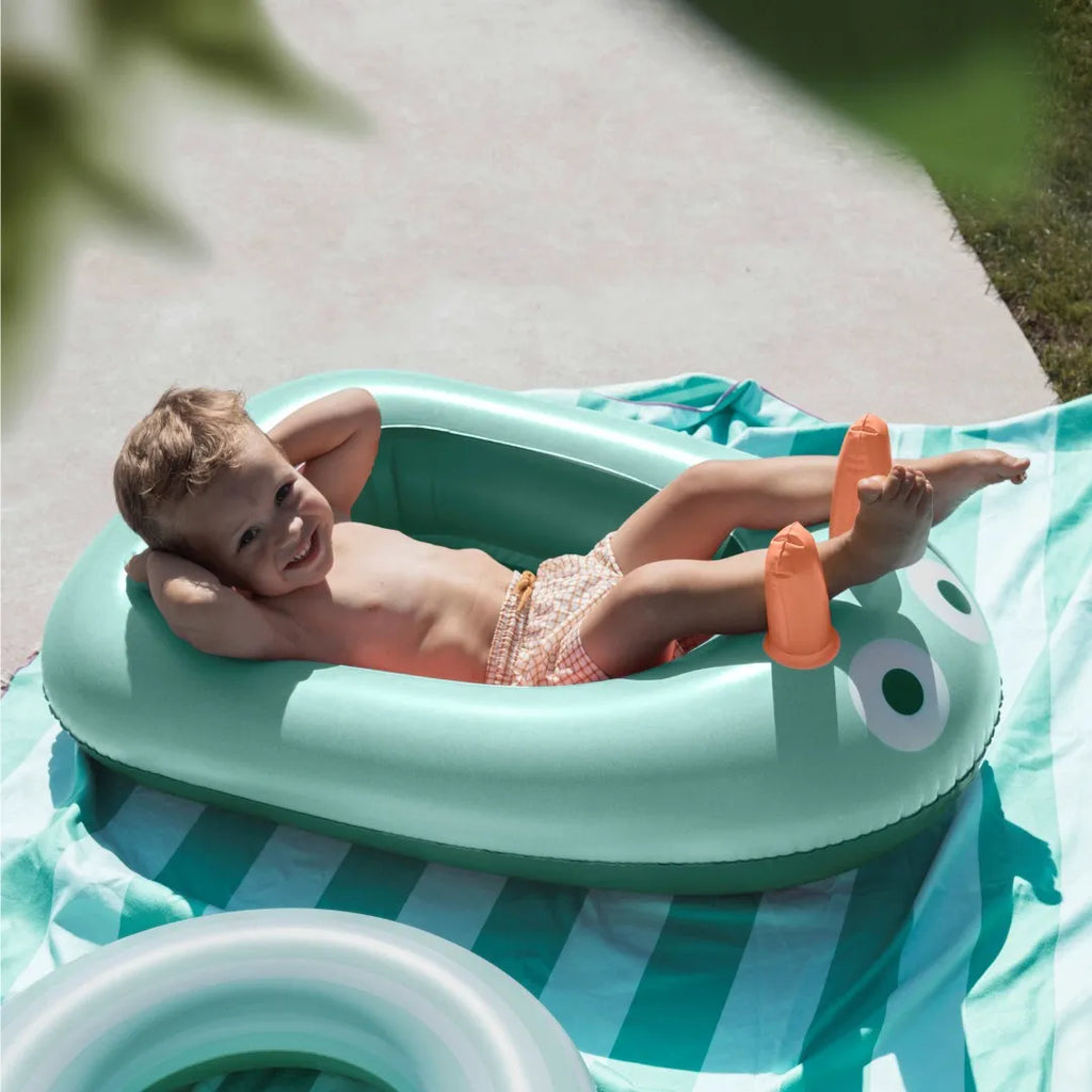 Young child using an inflatable boat during bath time fun