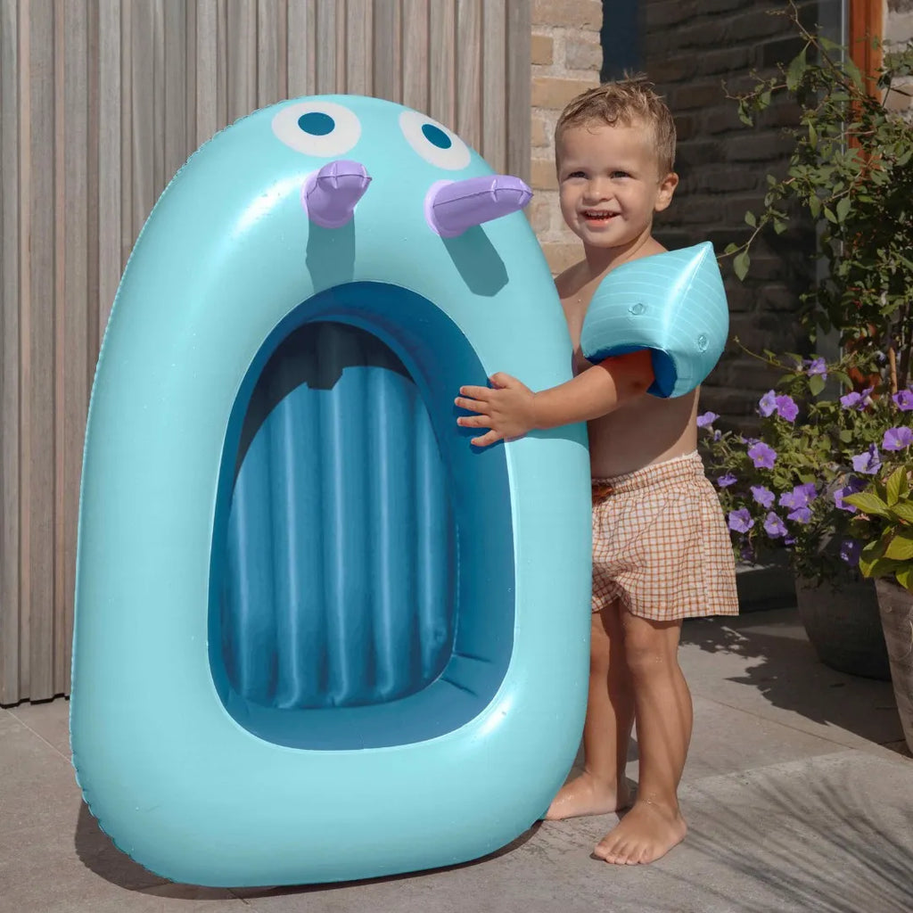Toddler sitting in an inflatable boat while exploring water play