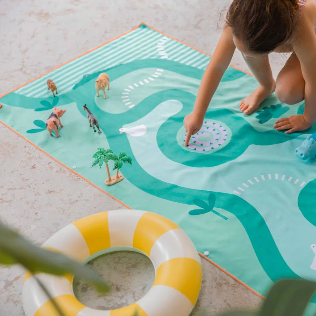 Kids playing on safari-themed double-sided play towel outdoors