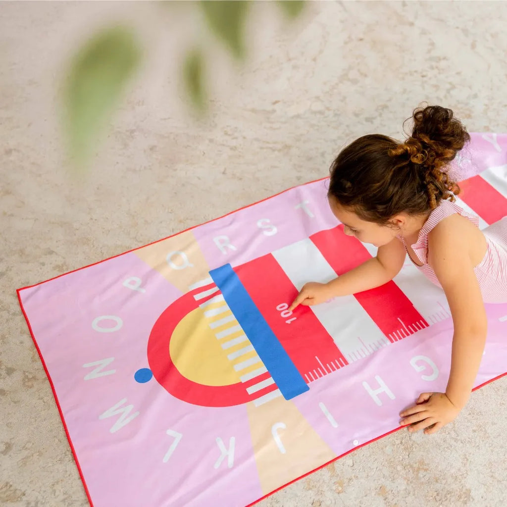 Kids playing a lighthouse-themed game on a beach play towel