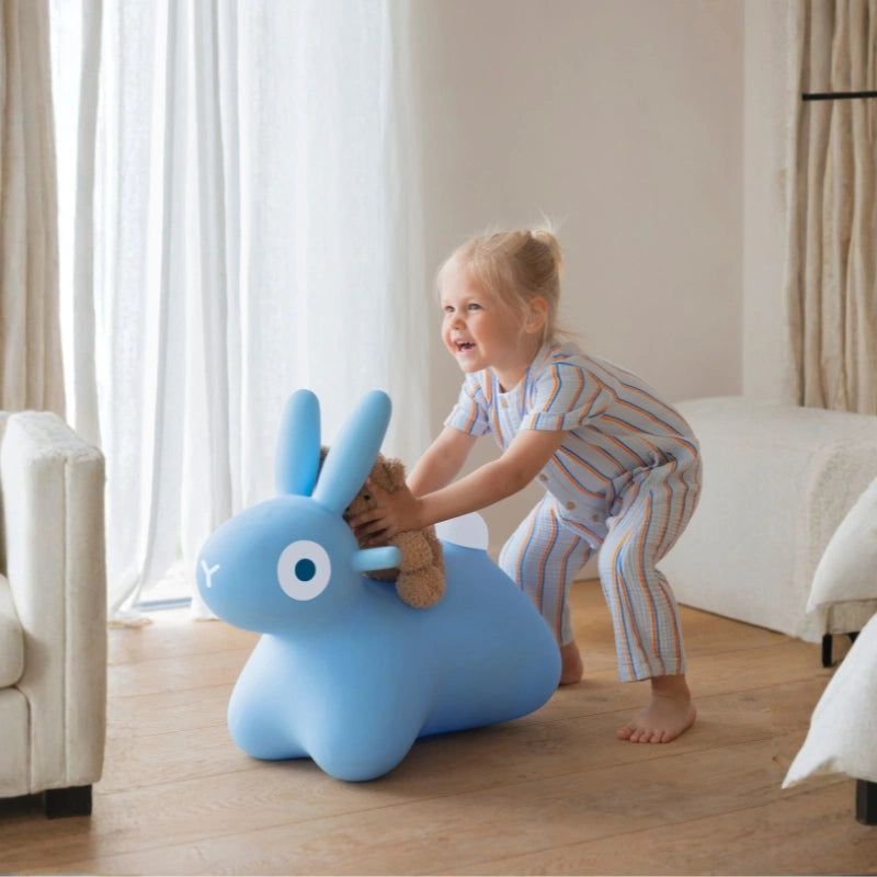 Toddlers hopping and laughing on an inflatable bunny ride-on toy during active play
