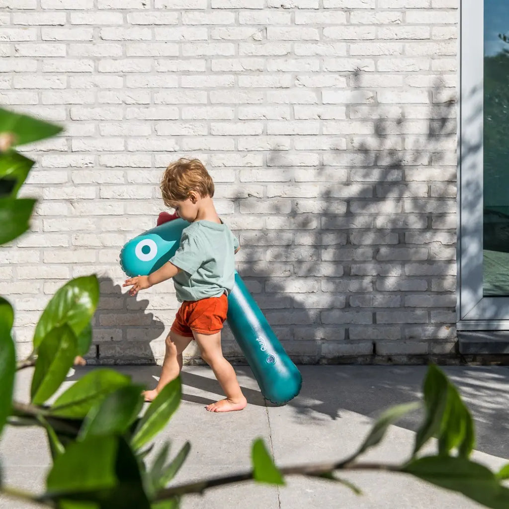 Child riding Noodle Dino as a hobby horse in the garden