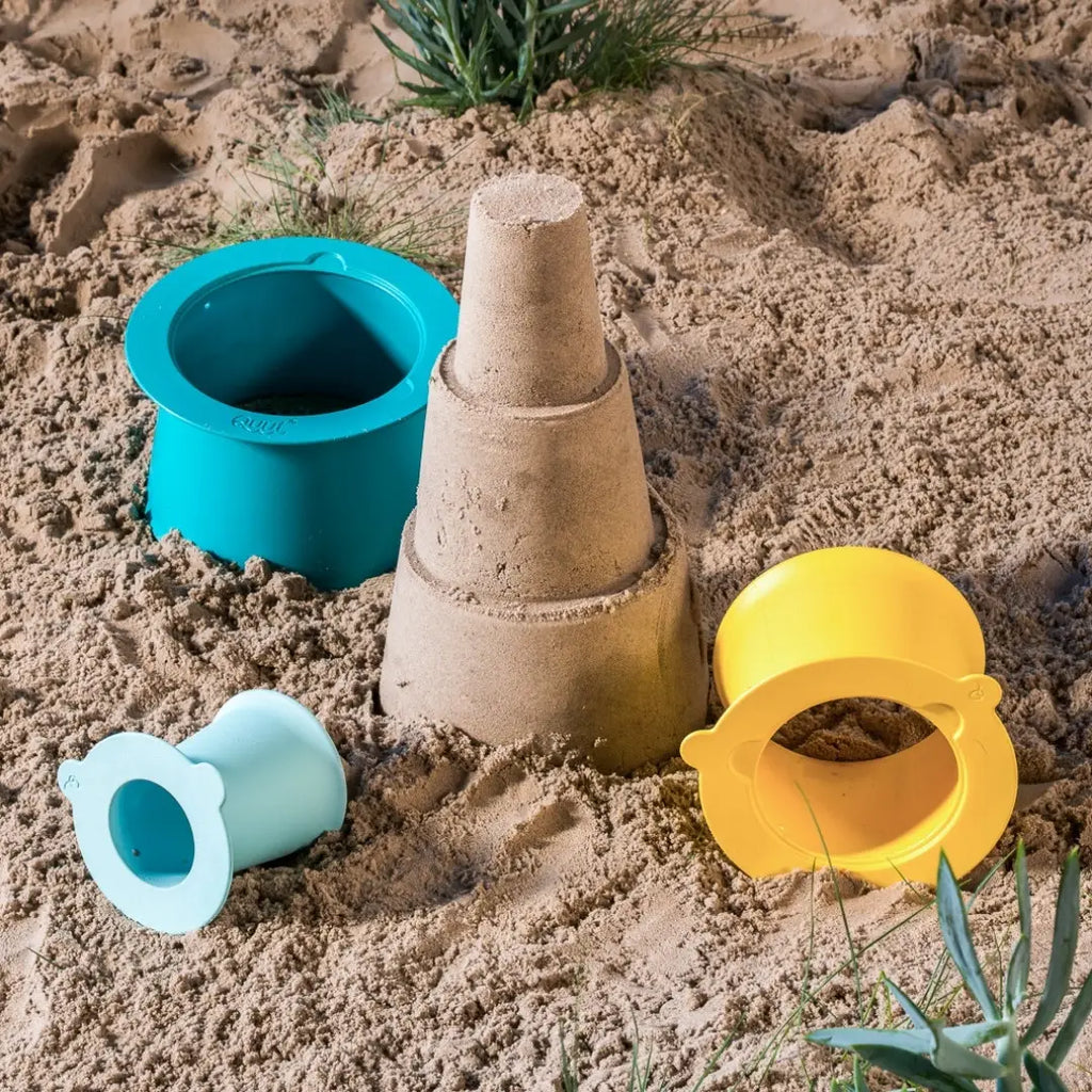 Toddler stacking vintage lagoon Alto sandcastle pieces on the beach