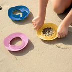 Toddler tapping and lifting Magic Shapers molds in snow play