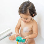Child playing with floating Beedi Croco lacing beads in the bathtub