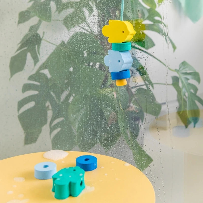 Child playing with floating Beedi Fish lacing beads in the bathtub