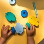 Toddler lacing Beedi Fish foam beads during bath time play