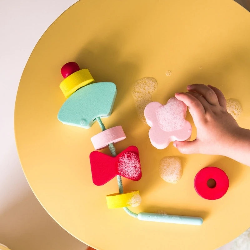 Toddler playing with Beedi Shapes floating foam beads during bath time