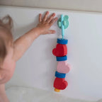Toddler exploring sensory play with Beedi Hearts foam beads in water