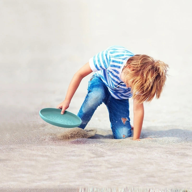 Toddler using the disc as a sand sifter on the beach