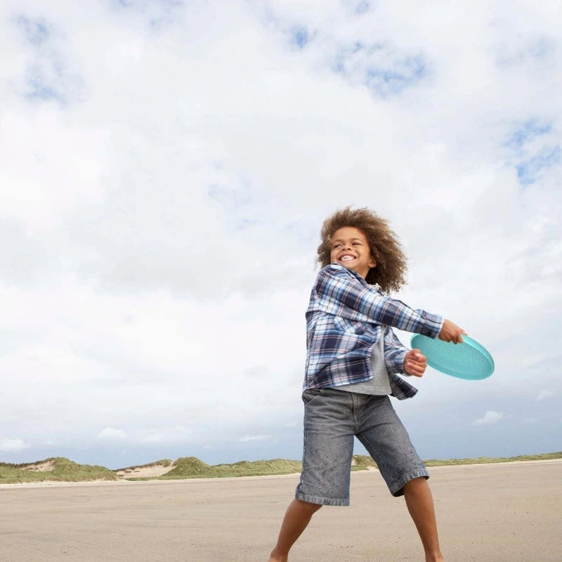 Kid throwing the flying disc at the beach
