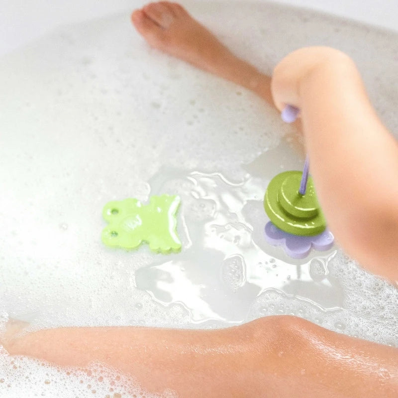 Child sticking foam frogs and water lilies on tub wall
