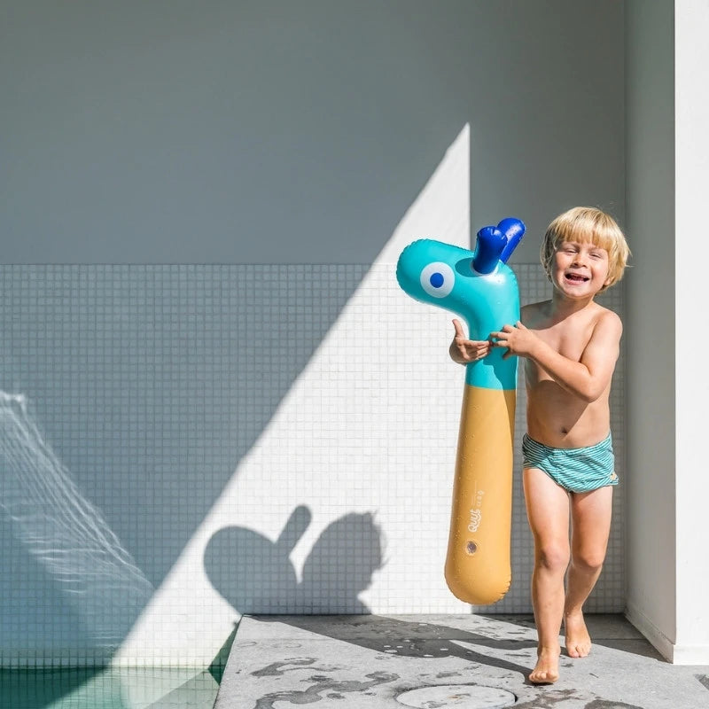 Toddler holding Noodle Giraffe while hopping and laughing outdoors