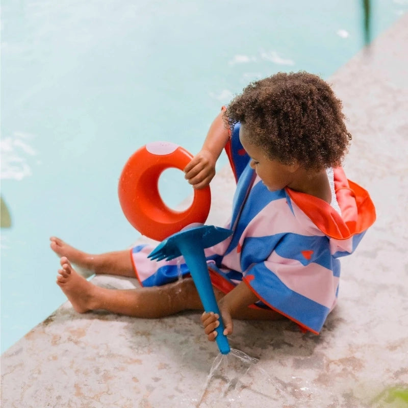 Child stepping out of the pool wrapped in colorful poncho