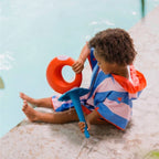 Child stepping out of the pool wrapped in colorful poncho