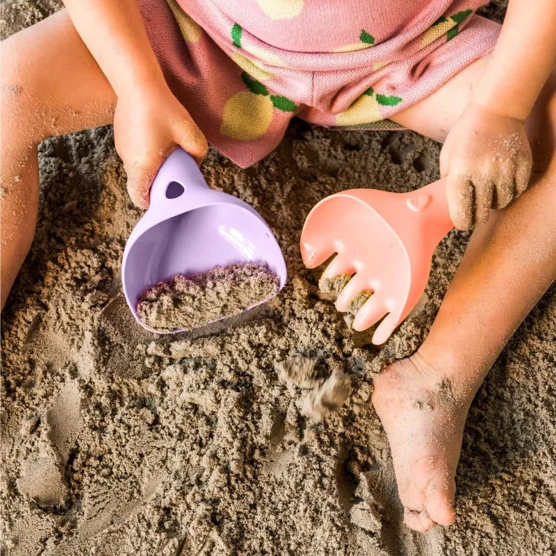 Child using Raki to rake and smooth sand during outdoor play