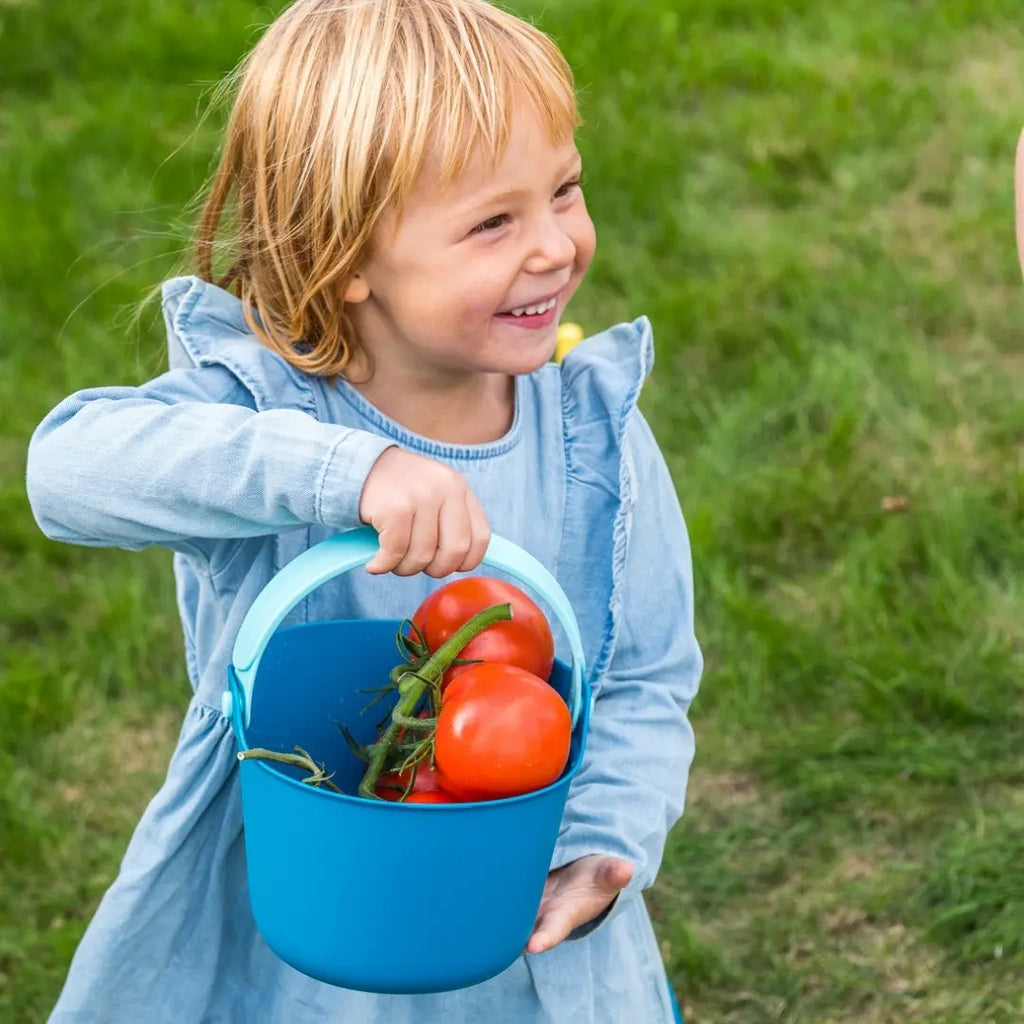 Toddler collecting sand with Bucki Spill-Proof Bucket at the beach