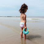 Toddler holding Cana while looking on the sea