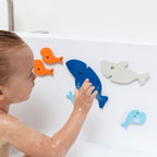 Toddler sticking floating Bath Puzzle Shark pieces to the tub wall