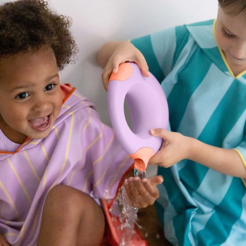 Toddler pouring water with a Cana watering can in the bathtub