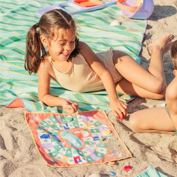 Children rolling dice and climbing ladders on a travel Snakes & Ladders board