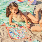 Children rolling dice and climbing ladders on a travel Snakes & Ladders board