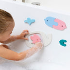 Toddler sticking floating whale puzzle pieces to the bath wall