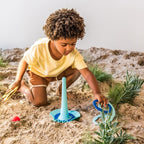 Child using Triplet on the sand for building and pouring