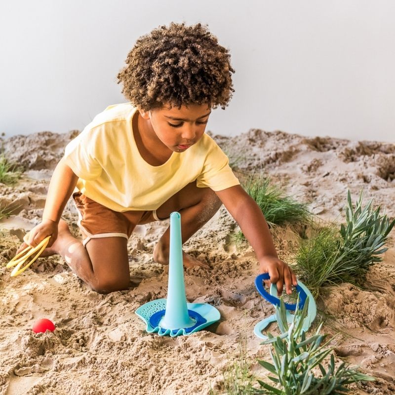 Child using Triplet on the sand for building and pouring