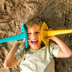 Child playing in sand with a blue and yellow shovel toy