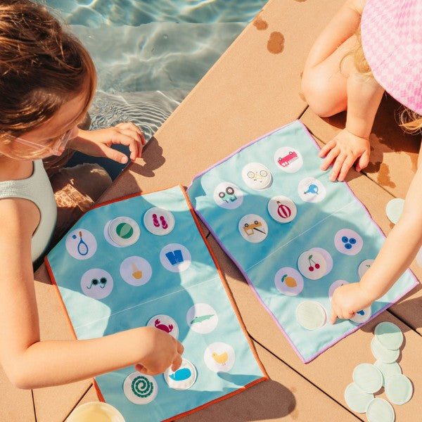 Toddlers placing markers on a Lotocolor game board at home