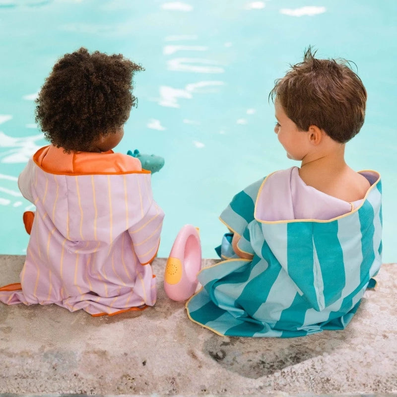 Young child wearing poncho over swimwear at the seaside