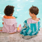 Young child wearing poncho over swimwear at the seaside