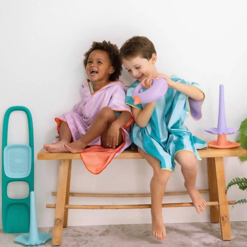 Child smiling in poncho while collecting seashells