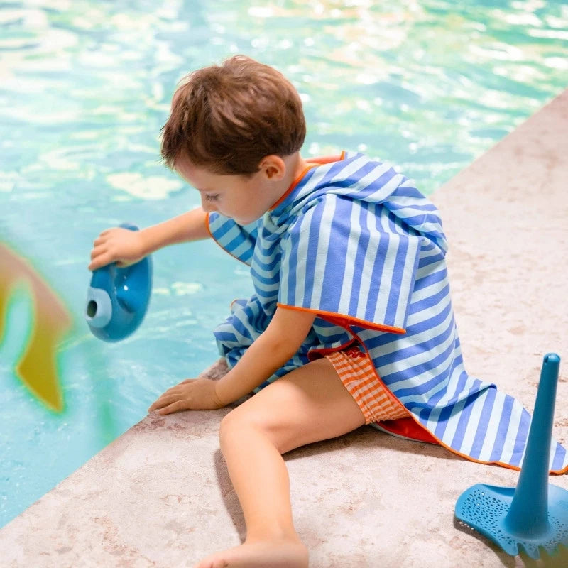 Young child wearing poncho while building sandcastles, sand-free
