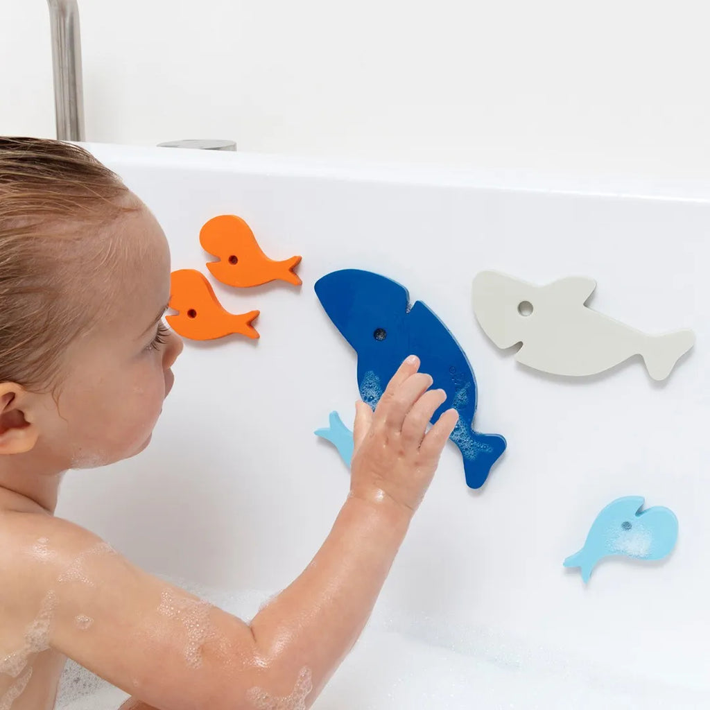 Child arranging floating shark and fish pieces during bath play
