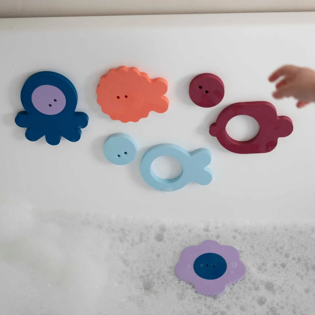 Child arranging colorful floating sea creatures during bath play