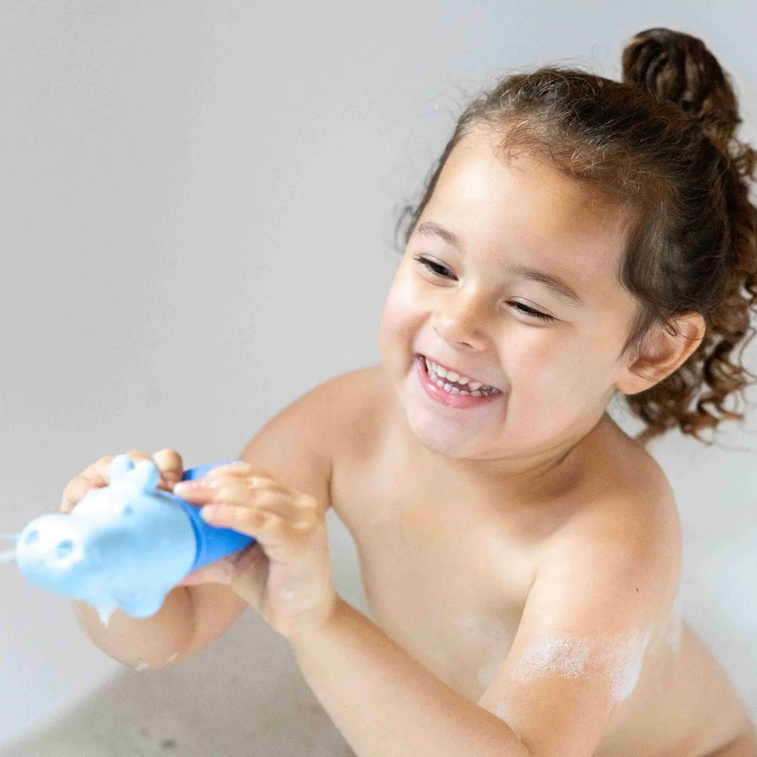 Toddler engaging in imaginative play with Squeezi Hippo in the tub